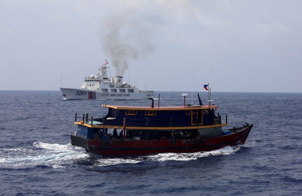 A Philippine supply boat sails near a Chinese Coast Guard ship during a resupply mission for Filipino troops stationed at a grounded warship in the South China Sea, 4 October 2023 (Photo: Reuters/Adrian Portugal).