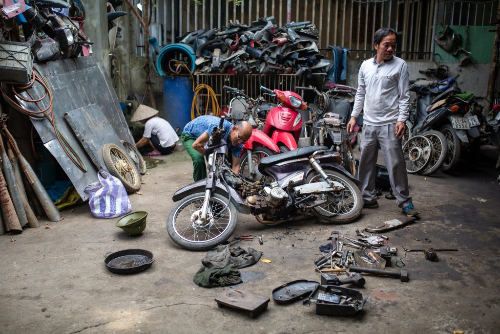 Workers at a motorcycle recycling yard perform maintenance in front of their home in Vietnam, 3 May 2021 (Photo: Reuters/Chris Humphrey).