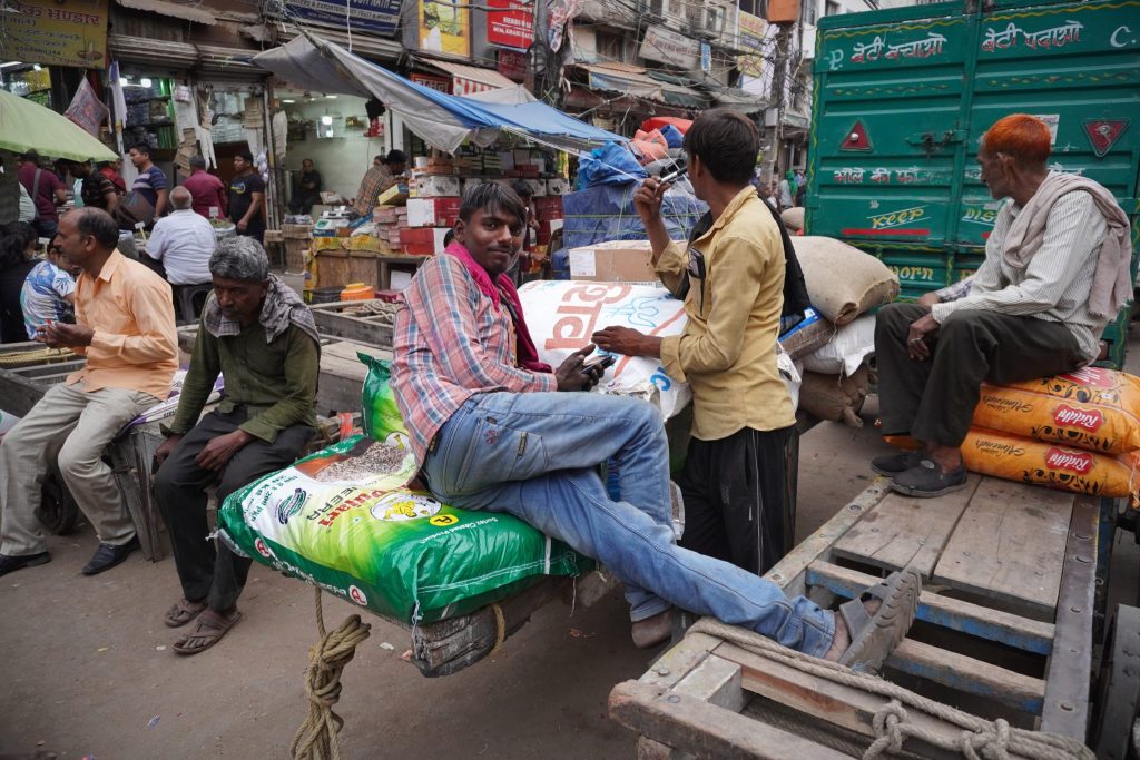 A labourer rests on a cart loaded with sacks along a roadside at a wholesale grain market in the old quarters of Delhi, India, 29 April 2023 (Photo: Mayank Makhija/NurPhoto via Reuters).