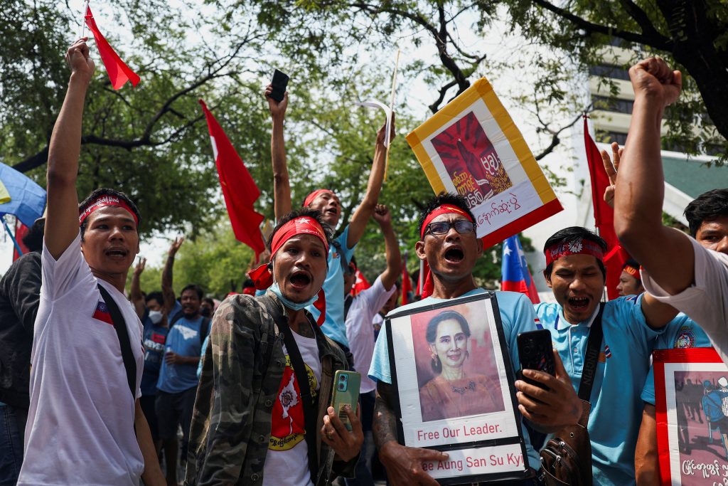 Protesters hold up a portrait of Aung San Suu Kyi and raise three-finger salutes during a demonstration to mark the third anniversary of Myanmar’s 2021 military coup, outside of the United Nations office in Bangkok, Thailand, 1 February 2024 (Photo: Reuters/Chalinee Thirasupa).