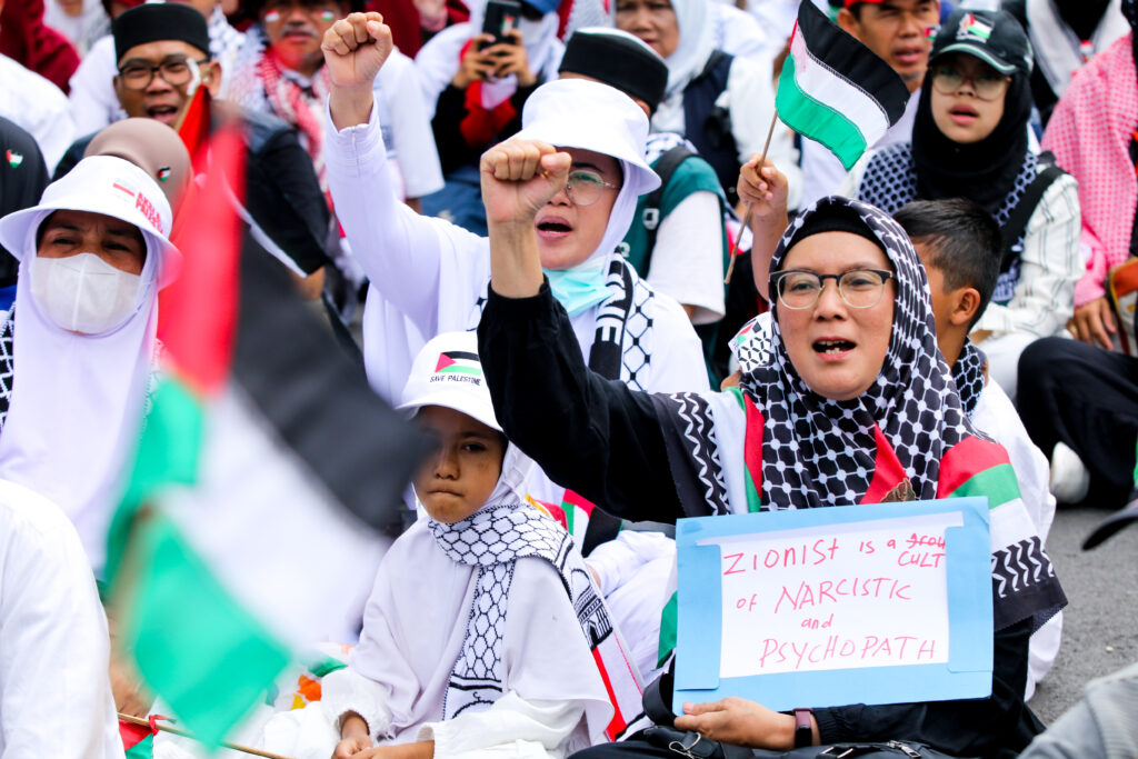 A number of residents are holding posters during a pro-Palestine demonstration in front of Gedung Sate, in Bandung, Indonesia, on 13 2024 (Photo: Reuters/Ryan Suherlan/NurPhoto).