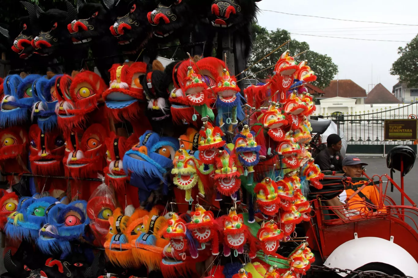 Rickshaw drivers are sitting and waiting for passengers next to lion dance decorations that are for sale on Malioboro Street in Yogyakarta, Indonesia, 7 March 2024 (Photo: Angga Budhiyanto/NurPhoto)