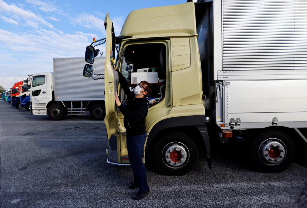 A truck driver cleans his truck as he takes a break at a parking area, Tokyo, Japan, 6 April 2023 (Photo: Reuters/Issei Kato).