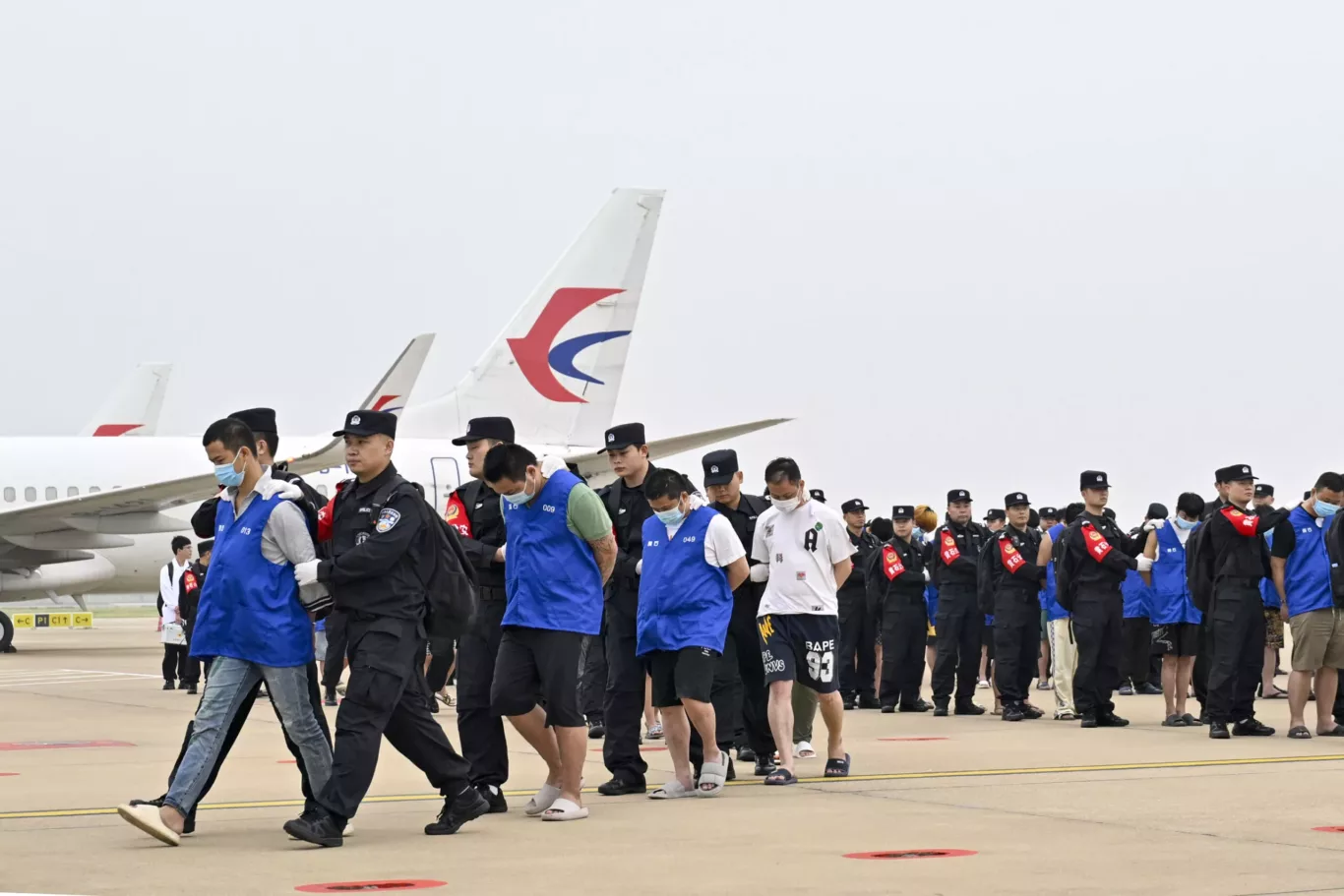 Chinese gambling and scam suspects are escorted by the police at Wuhan Tianhe International Airport in Wuhan, China, on 13 April 2024 (Photo: Zhao Wenyu/China News Service/VCG via Reuters Connect)