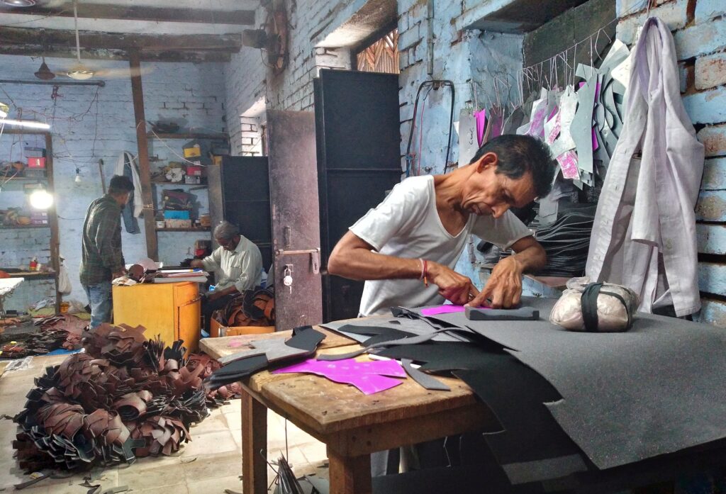 A worker cuts synthetic leather to make shoes in Agra, India, 30 May 2022 (Photo: Reuters/Manoj Kumar).