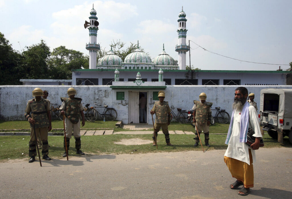 A Hindu priest walks past paramilitary troopers guarding a mosque as Muslims offer Friday prayers in the northern Indian town of Ayodhya 1 October 2010. Indian Muslim clerics and community leaders rallied on Friday against a court verdict in India's most religiously divisive case that largely favoured Hindus, highlighting possible communal tensions (Photo: REUTERS/Mukesh Gupta).